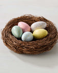 Nest with pastel-colored eggs on a light background