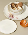 A set of white dinnerware including one large plate, one medium plate, one large bowl, and one medium bowl, all with a wide rim
