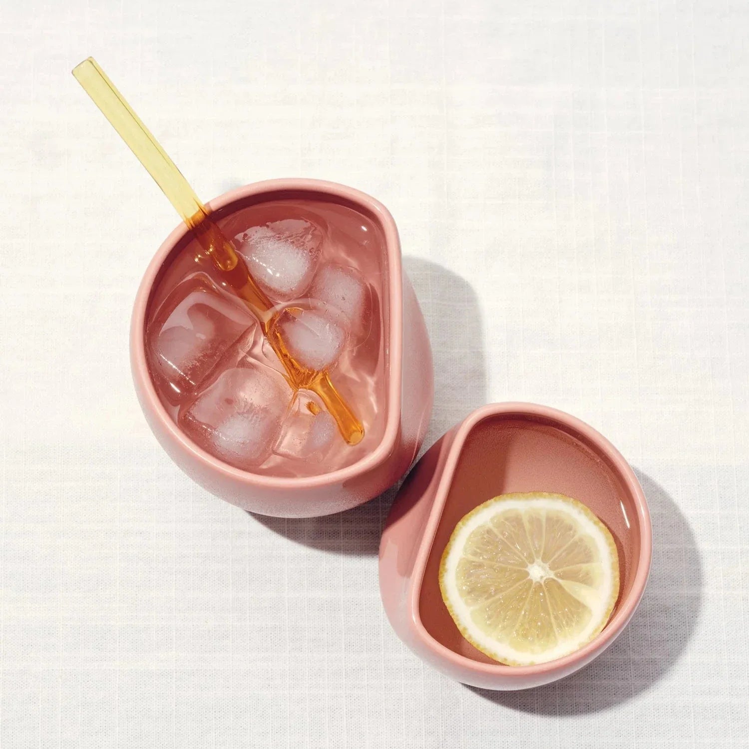 A large pink ceramic coffee cup with a latte art design, accompanied by peanuts on the side, presented on a neutral background.