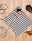 A person wearing a striped waist apron with spoons in its pockets.