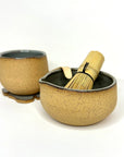 Ceramic tea set with two bowls and a whisk on a white background