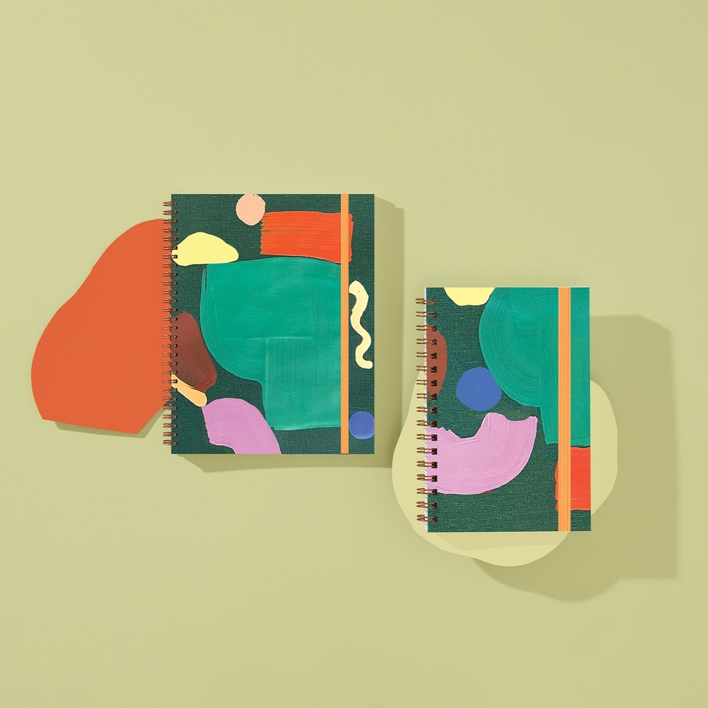 Two spiral-bound notebooks with colorful abstract designs on a beige background