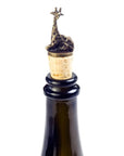 A brass giraffe-shaped wine bottle stoppers sitting atop corks on top of a wine bottle.