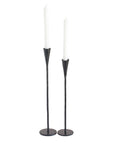 Two black candle holders with white candles on a white background