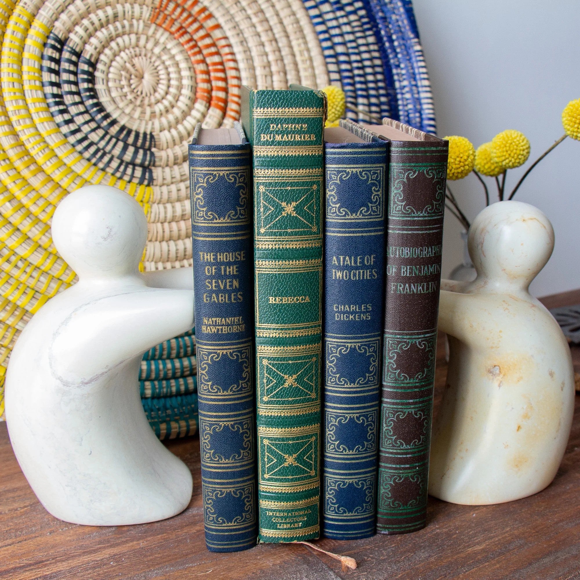 A pair of hand-carved soapstone helping hands bookends holding a set of four books