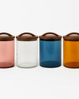 Four colorful glass jars with wooden lids on a white background