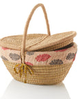 An oval-shaped kaisa grass and jute picnic basket with a handle and two flaps displayed against a white background