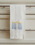 White tea towel with Menorah design hanging on a cabinet door