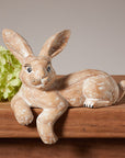 A handmade whitewashed wooden hare shelf sitter sitting on a wooden shelf