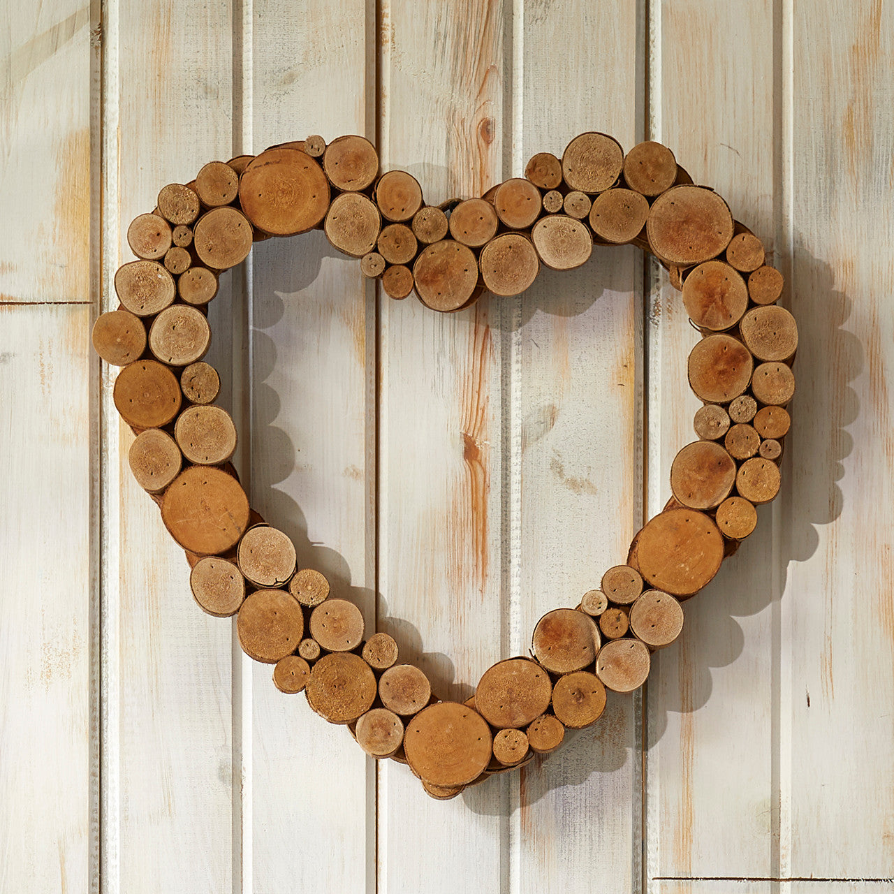 A heart-shaped wreath made from coral tree wood hanging on a wooden door