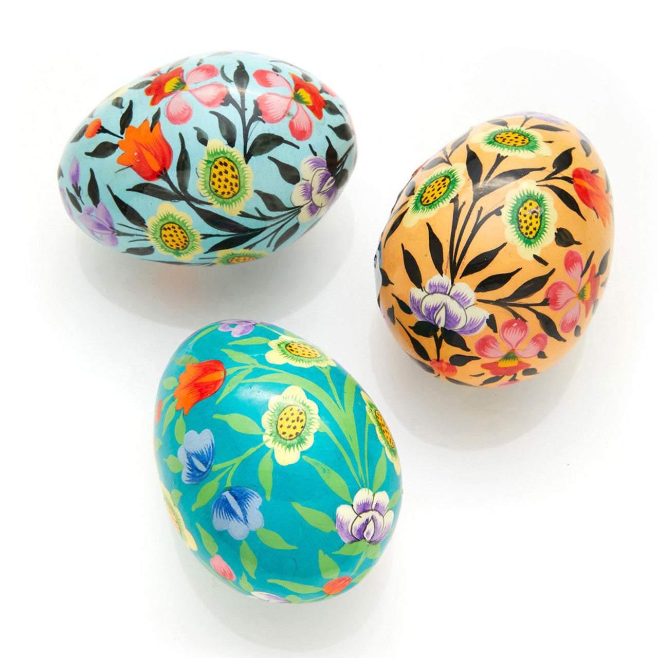 A set of three hand-painted wooden eggs with floral patterns in vibrant colors