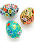 A set of three hand-painted wooden eggs with floral patterns in vibrant colors