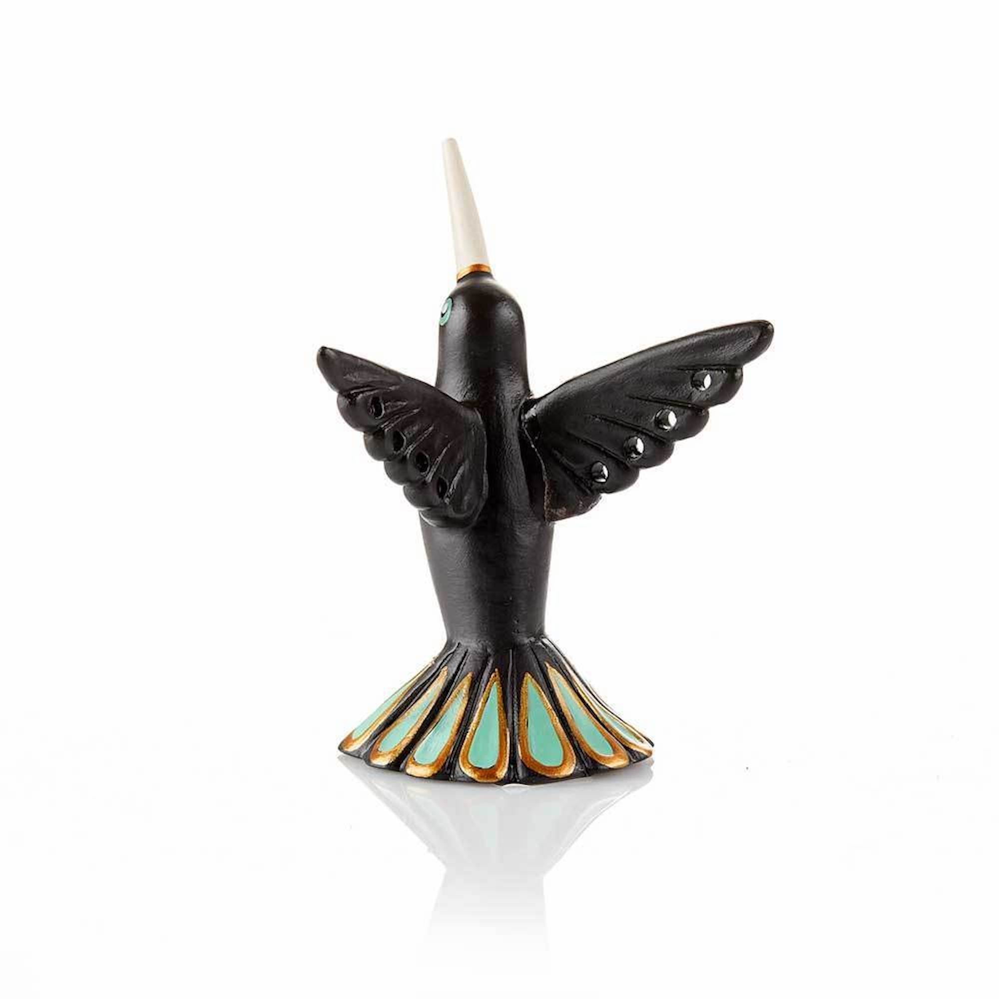 The back of a hand-painted ceramic jewelry holder in the shape of a hummingbird holding rings and earrings.