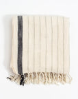 Beige towel with a black stripe and fringes on a white background
