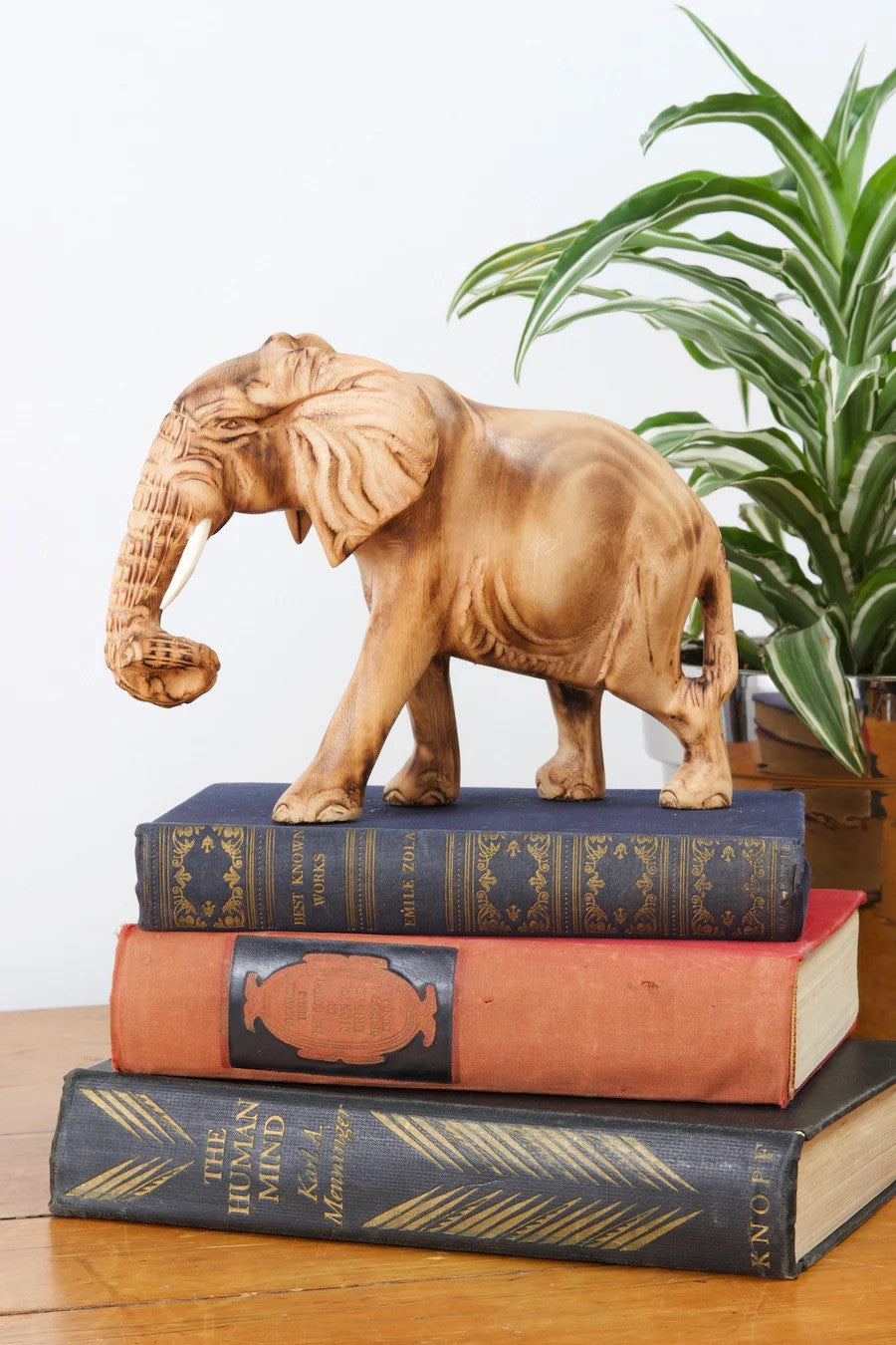 A sculpture of a jacaranda wood elephant on top of a set of books