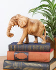 A sculpture of a jacaranda wood elephant on top of a set of books