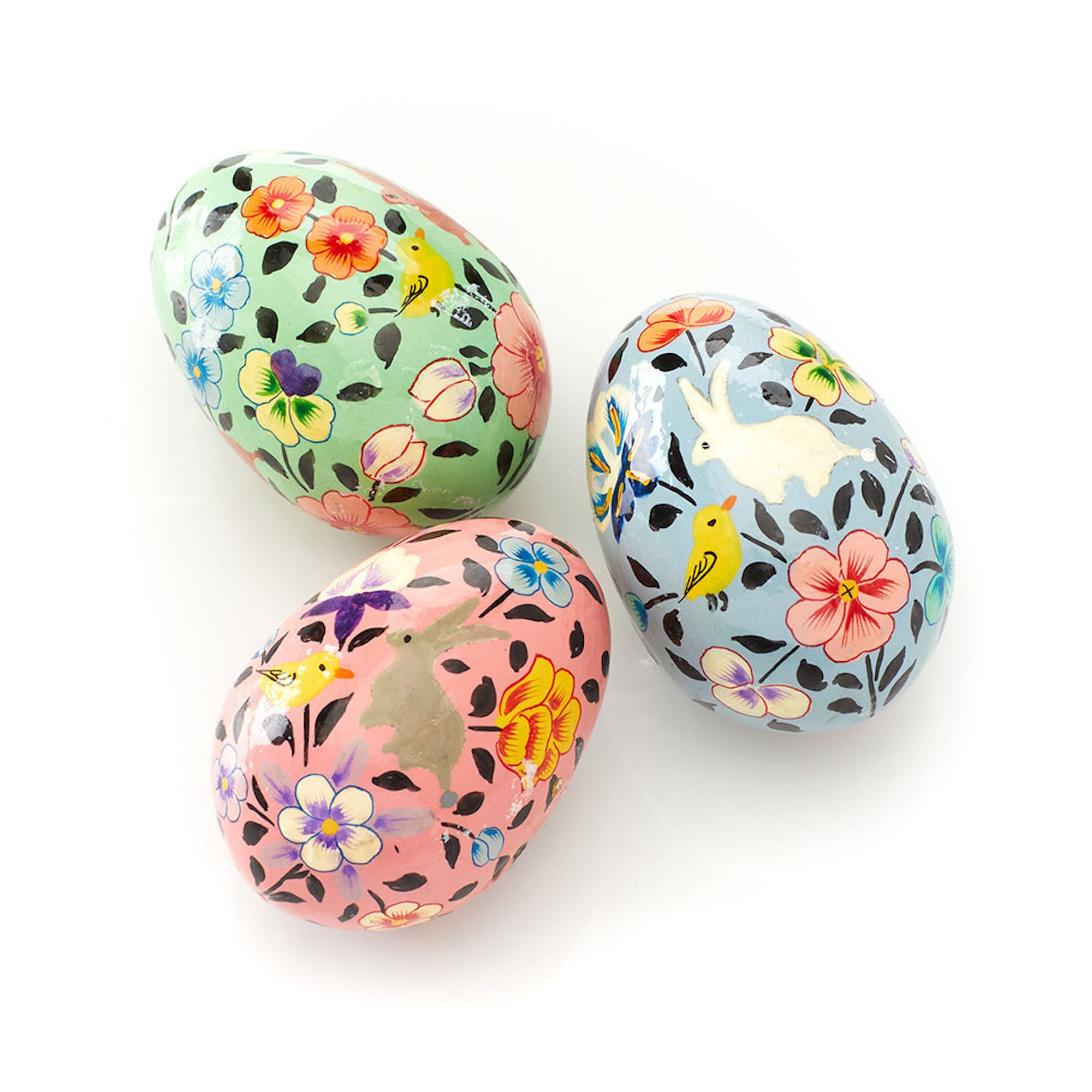 A set of three hand-painted wooden eggs with floral patterns and birds.
