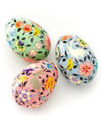 A set of three hand-painted wooden eggs with floral patterns and birds.