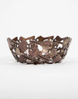 A side view of a handcrafted decorative bowl made of assorted recycled iron keys with a copper-colored finish.