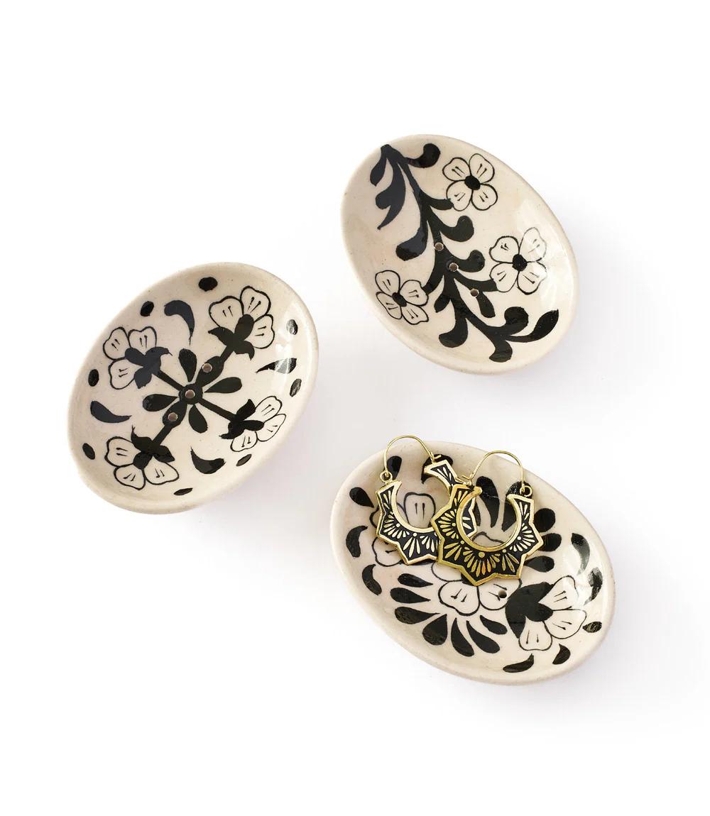 Three ceramic plates with black floral patterns on a white background