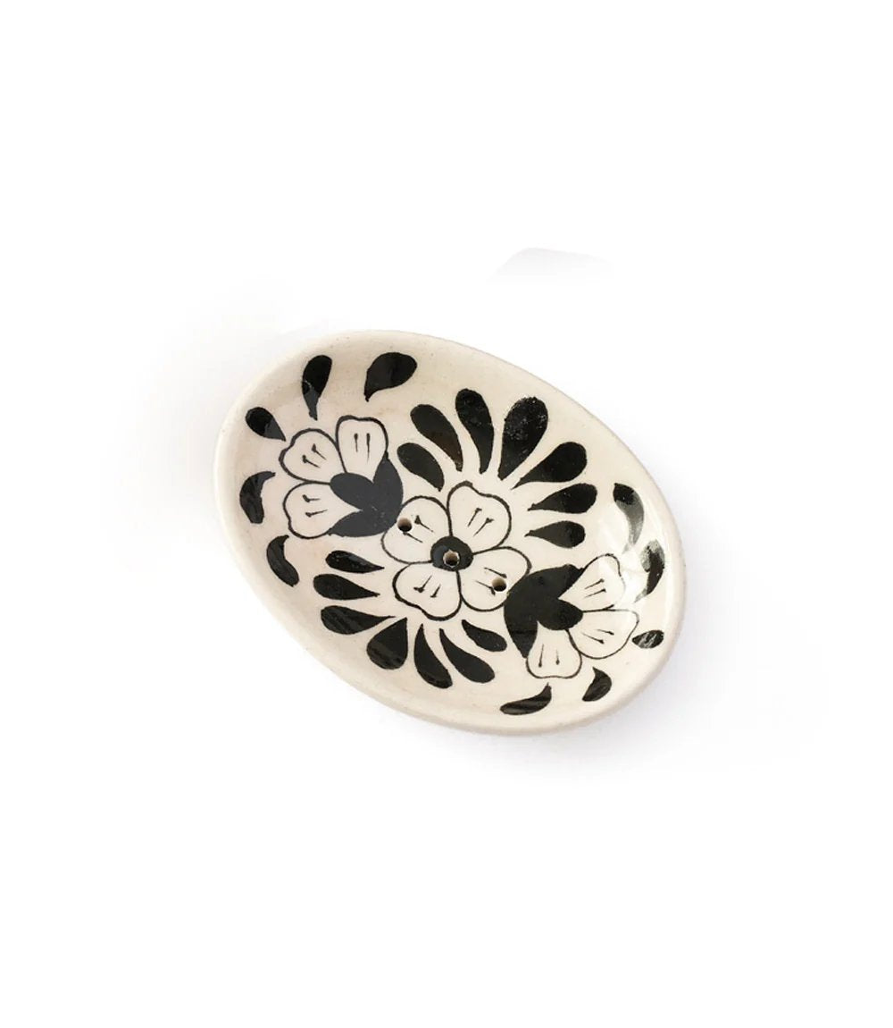 Round ceramic dish with black floral patterns on a white background