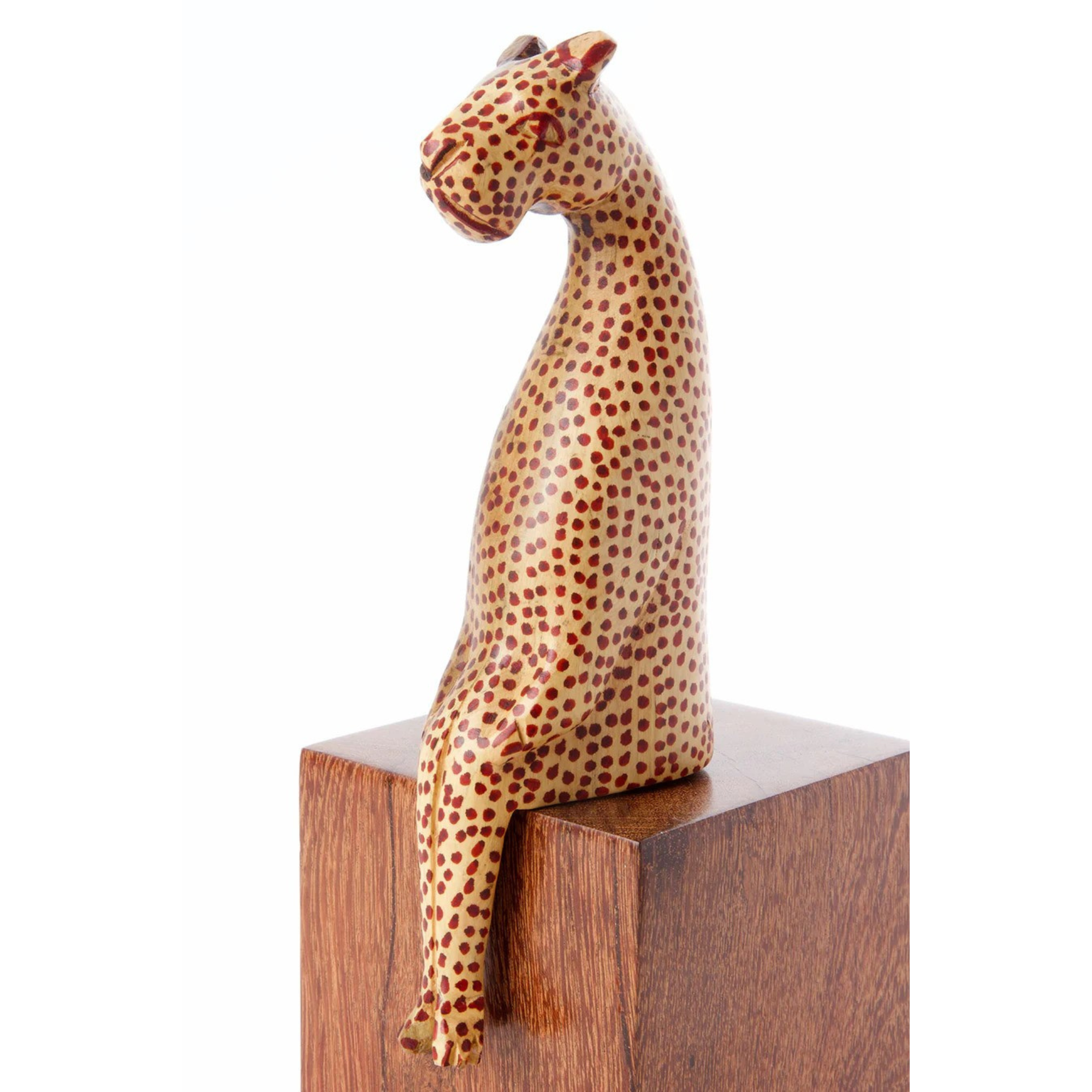 A handcrafted wooden leopard figurine with hand-painted spots, perched on a wooden shelf