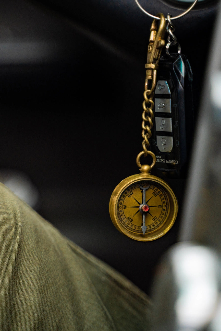 Gold compass keychain on a blurred background