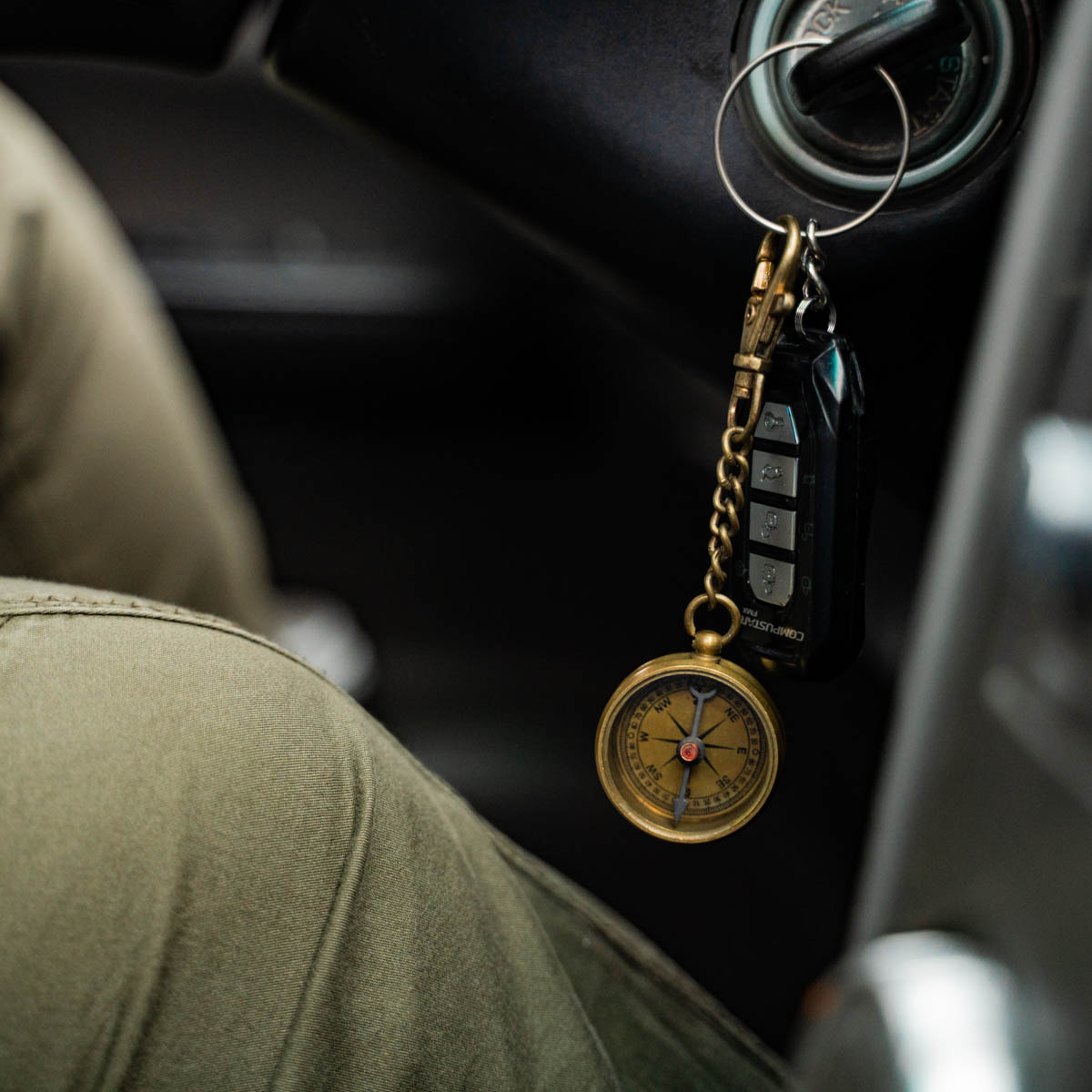 Keychain with compass and car key fob inside a vehicle