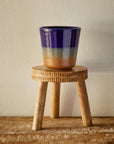 A wooden plant stand holding a multi-color planter