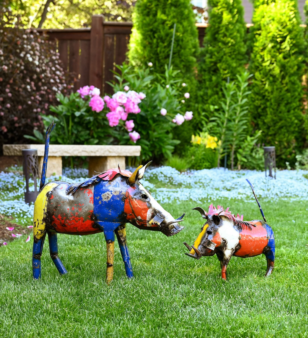 Colorful metal pig sculptures in a garden setting with flowers and a bench.