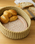 Woven bread basket with bread rolls on a wooden table