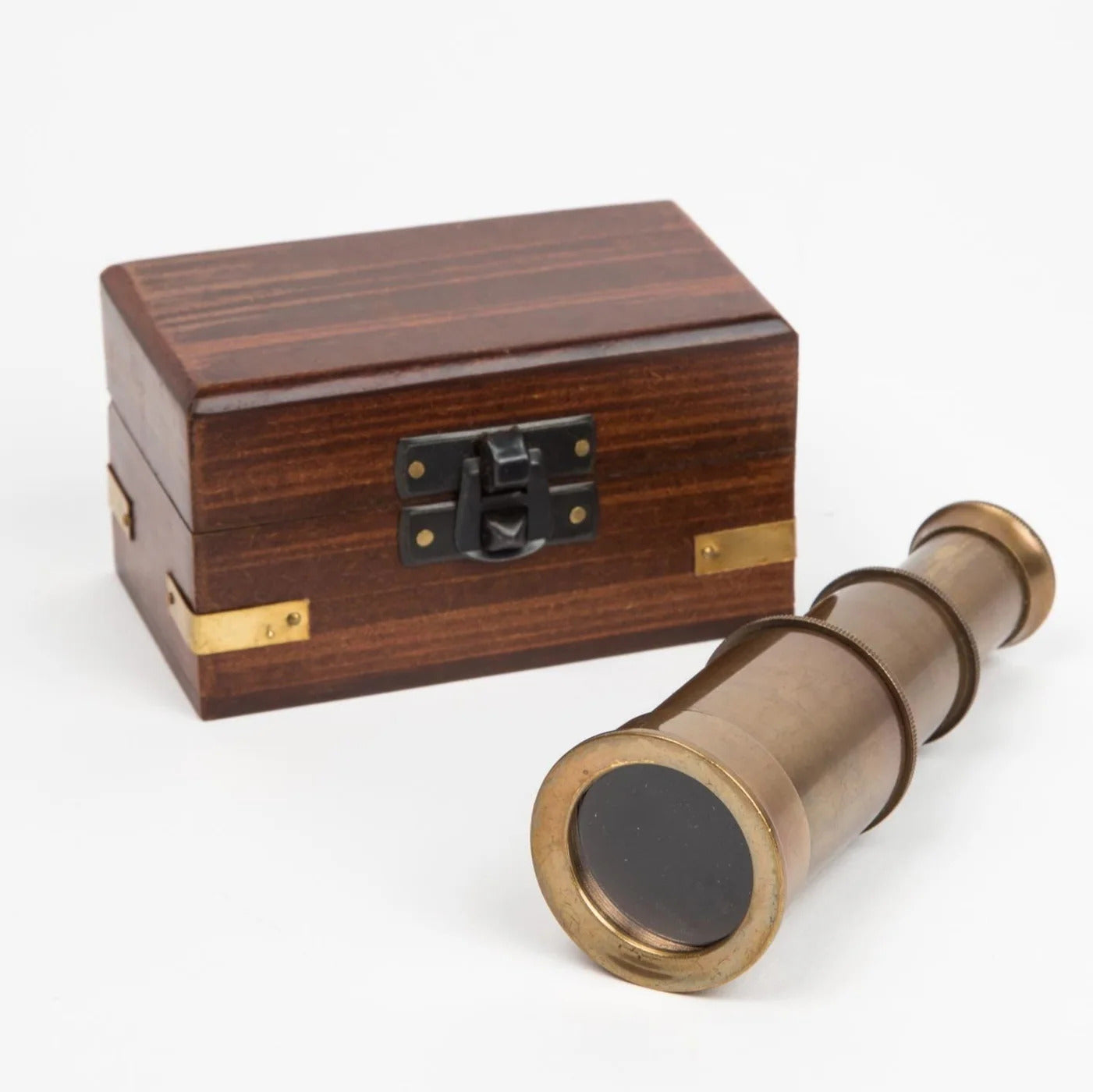 Mini brass telescope with an antique finish displayed next to its velvet-lined wooden storage box on a neutral surface.