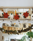 Decorative garland with red, white, and green flowers hanging above a mirror