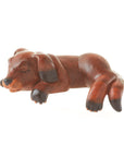 A carved wooden figurine of a sleeping dog with a brown stain finish, designed to sit on a shelf