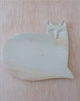 A handcarved stone dish designed as a cat placed on a wooden surface