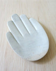 A handcarved stone dish shaped like a hand placed on a wooden desk