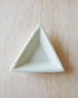 A natural stone mini triangle dish, hand carved and smoothed, placed on a beige surface