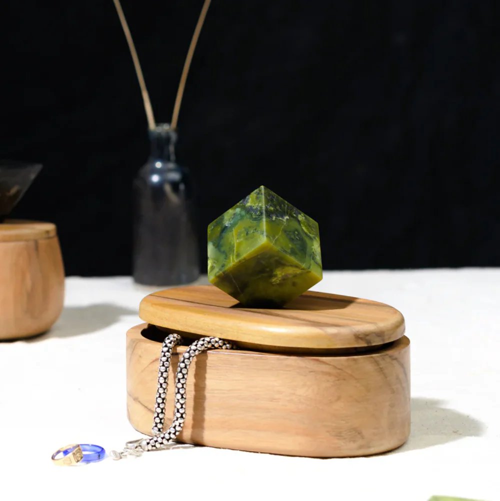 Wooden box with a green crystal on top, surrounded by dark background