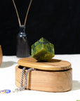 Wooden box with a green crystal on top, surrounded by dark background