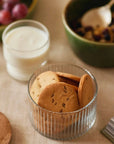 Glass jar with cookies inside next to a glass of milk