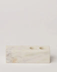 A rectangular marble candle holder with two circular indentations for candles