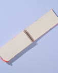 Open notebook with beige pages and red binding on a light blue background