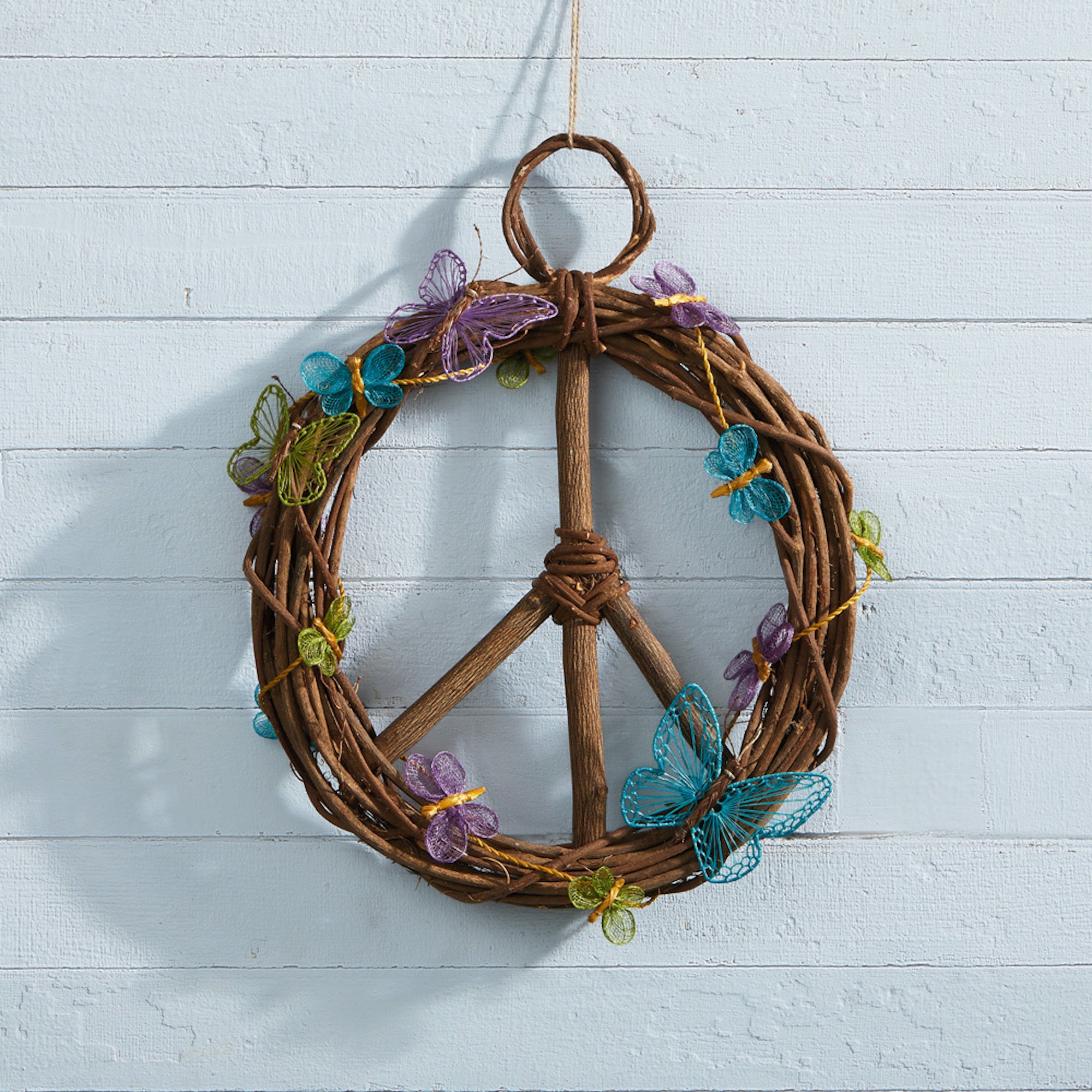 A round peace symbol wreath made from takip-asin wood and galtang vine with a butterfly designed blue, green, and purple garland
