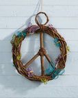 A round peace symbol wreath made from takip-asin wood and galtang vine with a butterfly designed blue, green, and purple garland