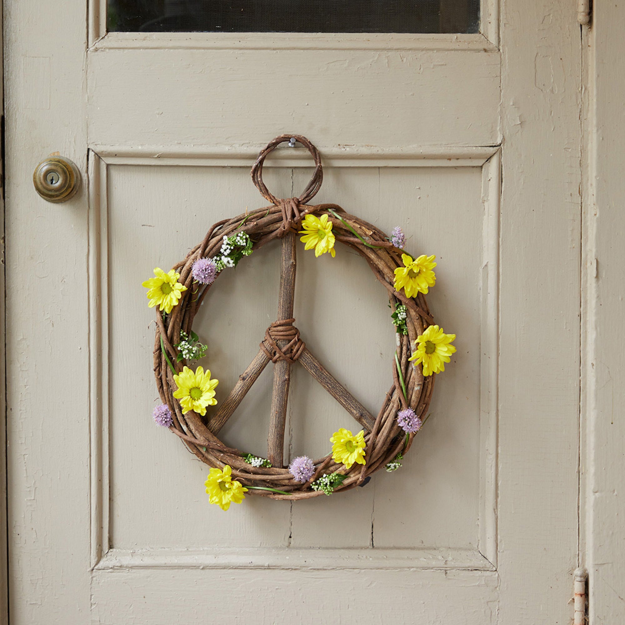 A wreath hanging on a door with yellow sunflowers decorated around it