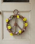 A wreath hanging on a door with yellow sunflowers decorated around it