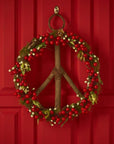 A wooden wreath with a peace symbol hanging on a door with christmas decorations