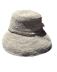 A pink raffia hat with a round shape and a flat brim, featuring a decorative ribbon around the crown.
