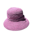 A pink raffia hat with a round shape and a flat brim, featuring a decorative ribbon around the crown.