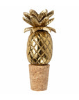 Gold pineapple-shaped bottle opener with cork base on a white background